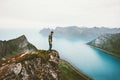 Man traveler standing alone on cliff mountain edge above fjord