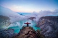 Man traveler standing on edge of crater Ijen volcano with colorful sky at morning