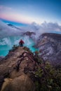 Man traveler standing on edge of crater Ijen volcano with colorful sky at morning