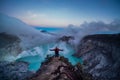 Man traveler standing on edge of crater Ijen volcano with colorful sky at morning