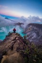 Man traveler standing on edge of crater Ijen volcano with colorful sky at morning