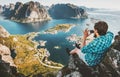 Man traveler taking aerial photo by smartphone sitting on cliff Royalty Free Stock Photo