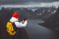 Man traveler taking photo with a smartphone hiking on Reinebringen mountain ridge in Norway lifestyle adventure traveling Royalty Free Stock Photo