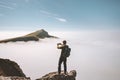 Man traveler taking photo by smartphone in mountains on cliff over clouds Royalty Free Stock Photo