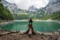 Man traveler on tree stump ejoying view of Dachstein peak mountains on a Upper Gosau Lake. Gosau, Salzkammergut, Austria Royalty Free Stock Photo