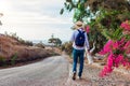 Man traveler walks along road in Akrotiri village on Santorini island Greece. Tourist backpacker admires flowers Royalty Free Stock Photo