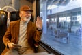 Man traveling in train and waving hand at station Royalty Free Stock Photo