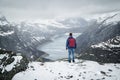 Man traveller with backpack standing back on edge and looking at scenery mountain landscape under snow, Trolltunga Royalty Free Stock Photo