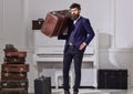 Man, traveller with beard and mustache with baggage, luxury white interior background. Macho stylish on strict face