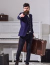 Man, traveller with beard and mustache with luggage, luxury white interior background. Baggage delivery concept. Macho