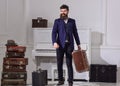 Man, traveller with beard and mustache with luggage, luxury white interior background. Baggage delivery concept. Macho
