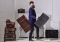 Man, traveller with beard and mustache with luggage, luxury white interior background. Macho elegant on cheerful face