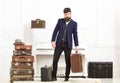 Man, traveller with beard and mustache with luggage, luxury white interior background. Macho elegant on strict face