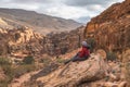 A man traveller sitting on rock and looking to landscape of Wadi Musa in Petra ruin and ancient city in Jordan