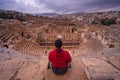 A man traveller sitting on top of Roman theater in Jerash ruin and ancient city of Roman empire in Amman city, Jordan, Arab