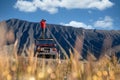 Man Traveller take a photo on a vintage off road car with Bromo mountain background Royalty Free Stock Photo