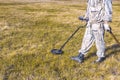 Man on a treasure hunt with a metal detector in the woods on the field