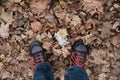 Man in trekking boots and jeans on the ground with dryed orange leaves