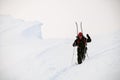 man with trekking poles walks through deep powdery snow on a mountain slope Royalty Free Stock Photo