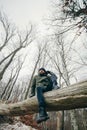 Man trekking in winter forest resting on tree. Royalty Free Stock Photo