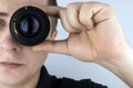 A man tries on a camera lens instead of an eye. The concept of the photographer`s work and the creative approach to photography