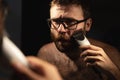 A man trims his beard in front of the mirror Royalty Free Stock Photo