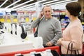 Man trying on headphones while shopping with his wife in electronic store Royalty Free Stock Photo