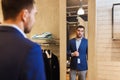 Man trying jacket on at mirror in clothing store Royalty Free Stock Photo