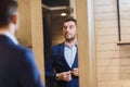 Man trying jacket on at mirror in clothing store Royalty Free Stock Photo