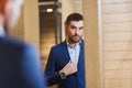 Man trying jacket on at mirror in clothing store Royalty Free Stock Photo