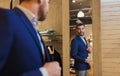 Man trying jacket on at mirror in clothing store Royalty Free Stock Photo