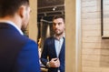 Man trying jacket on at mirror in clothing store Royalty Free Stock Photo