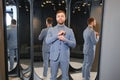 Man trying on suit jacket at mirror in menswear shop