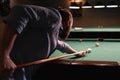 A man is trying to hit the ball in a billiards view from behind the shoulder. Billiard room in the background. Royalty Free Stock Photo