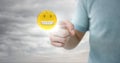 Man in tshirt pointing at emoji with flare against cloudy sky Royalty Free Stock Photo