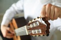 Man tunes classic guitar against dark background