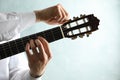 Man tunes classic guitar against light background