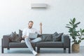 man turning on air conditioner with remote control while using laptop Royalty Free Stock Photo