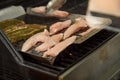 Man turning and roasting chicken filet and pork neck steaks on gas grill BBQ barbecue in stainless steel basket pan Royalty Free Stock Photo