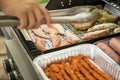 Man turning and roasting chicken filet, pork neck steaks, raw fresh sausages and marinated bacon wrapped skewers on gas grill BBQ Royalty Free Stock Photo