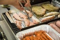 Man turning and roasting chicken filet, pork neck steaks, raw fresh sausages and marinated bacon wrapped skewers on gas grill BBQ Royalty Free Stock Photo