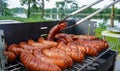 Man turning the sausage on the bbq with kitchen tongs. Person grilling in the garden. Royalty Free Stock Photo