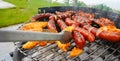 Man turning the sausage on the bbq with kitchen tongs. Person grilling in the garden. Royalty Free Stock Photo