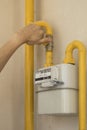 Man turning on or turning off gas supply on yellow gas pipe of meter measure household energy consumption