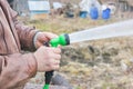 Man turns on the hose for watering plants with a sprayer.