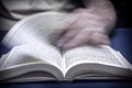 Man turns the page in an old little bible