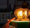 A man turns on round energy-efficient light bulbs in a glass bulb with warm light Royalty Free Stock Photo