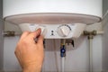 Man turns on the switch on control panel of home electric water heater boiler