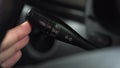 A man turns on the turn signal to the right on the lever in the car. Automotive panel close-up.