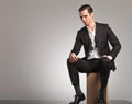 Man in tuxedo and undone bowtie resting on wooden box